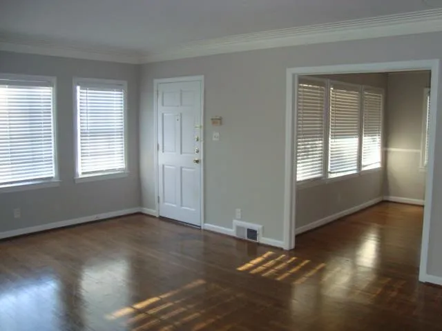 a view of an empty room with wooden floor and a window