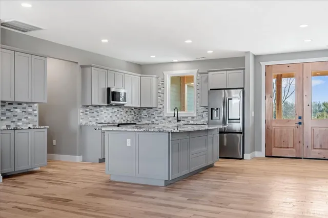 a kitchen with kitchen island granite countertop a sink cabinets and stainless steel appliances