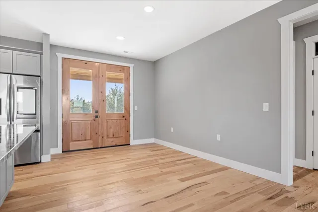 a view of an empty room with a window and wooden floor