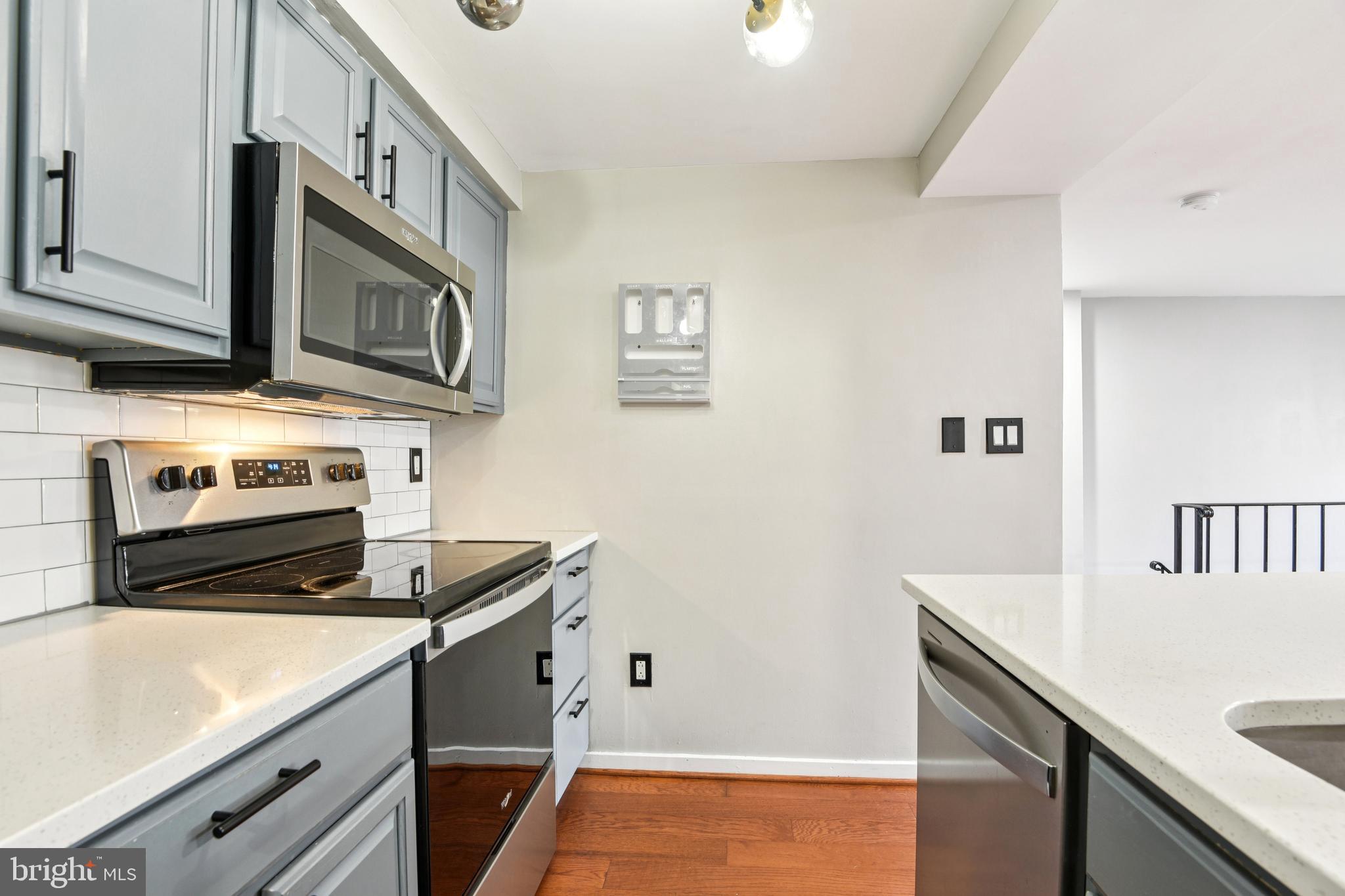 9717 Hellingly Place, Unit 48 Gaithersburg, MD 20886 - Photo 12 of 32 a kitchen with stainless steel appliances white cabinets and a stove top oven