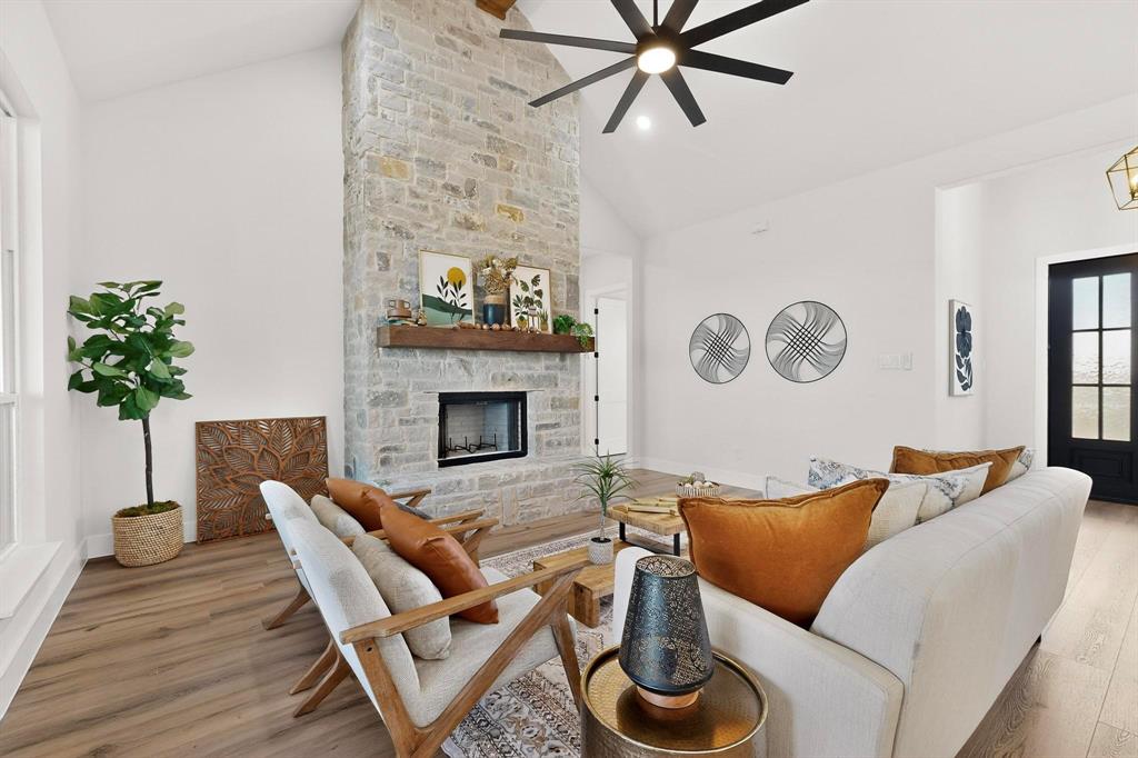 4961 County Road 1098 Celeste, TX 75423 - Photo 10 of 40 Living room with lofted ceiling, light wood finished floors, a stone fireplace, and ceiling fan