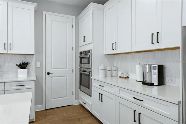 a kitchen with stainless steel appliances granite countertop a stove a sink a refrigerator a dining table and chairs with white cabinets