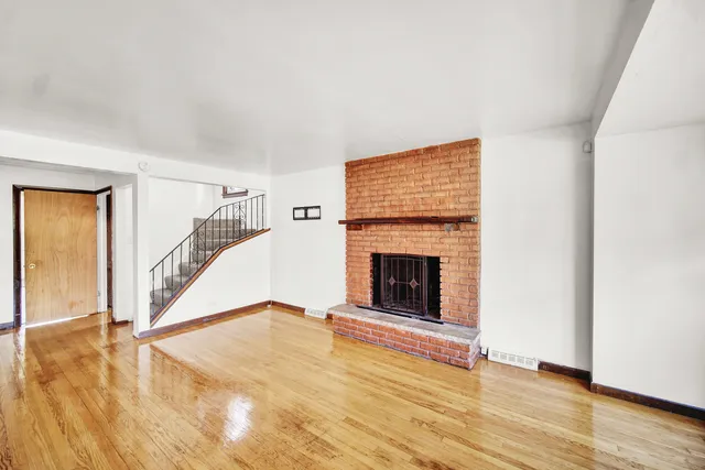 a view of a livingroom with wooden floor and a fireplace
