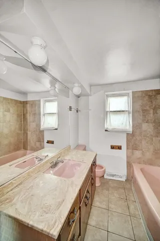 a spacious bathroom with a granite countertop sink a toilet a mirror and bathtub