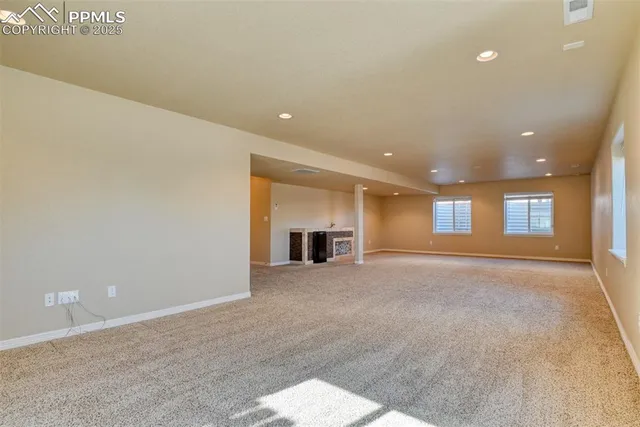 an empty room with windows and fireplace