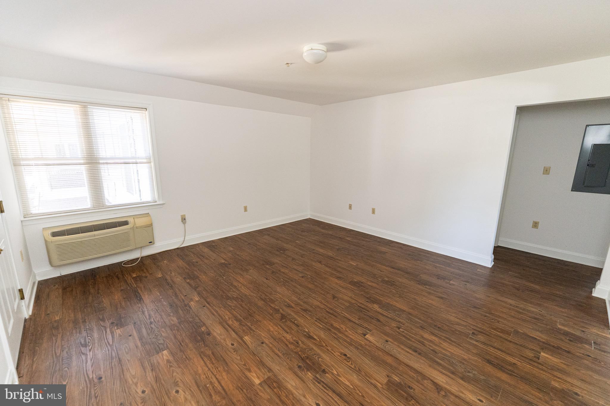 804 Travers Street, Unit 2 Cambridge, MD 21613 - Photo 6 of 26 an empty room with wooden floor and windows