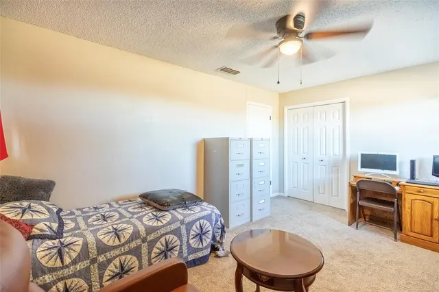 a spacious bedroom with a bed a dresser and a chandelier