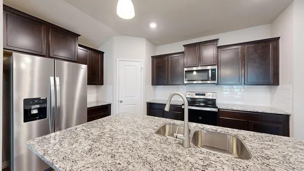 a kitchen with stainless steel appliances kitchen island granite countertop a refrigerator and a stove top oven
