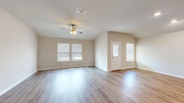 an empty room with wooden floor and windows