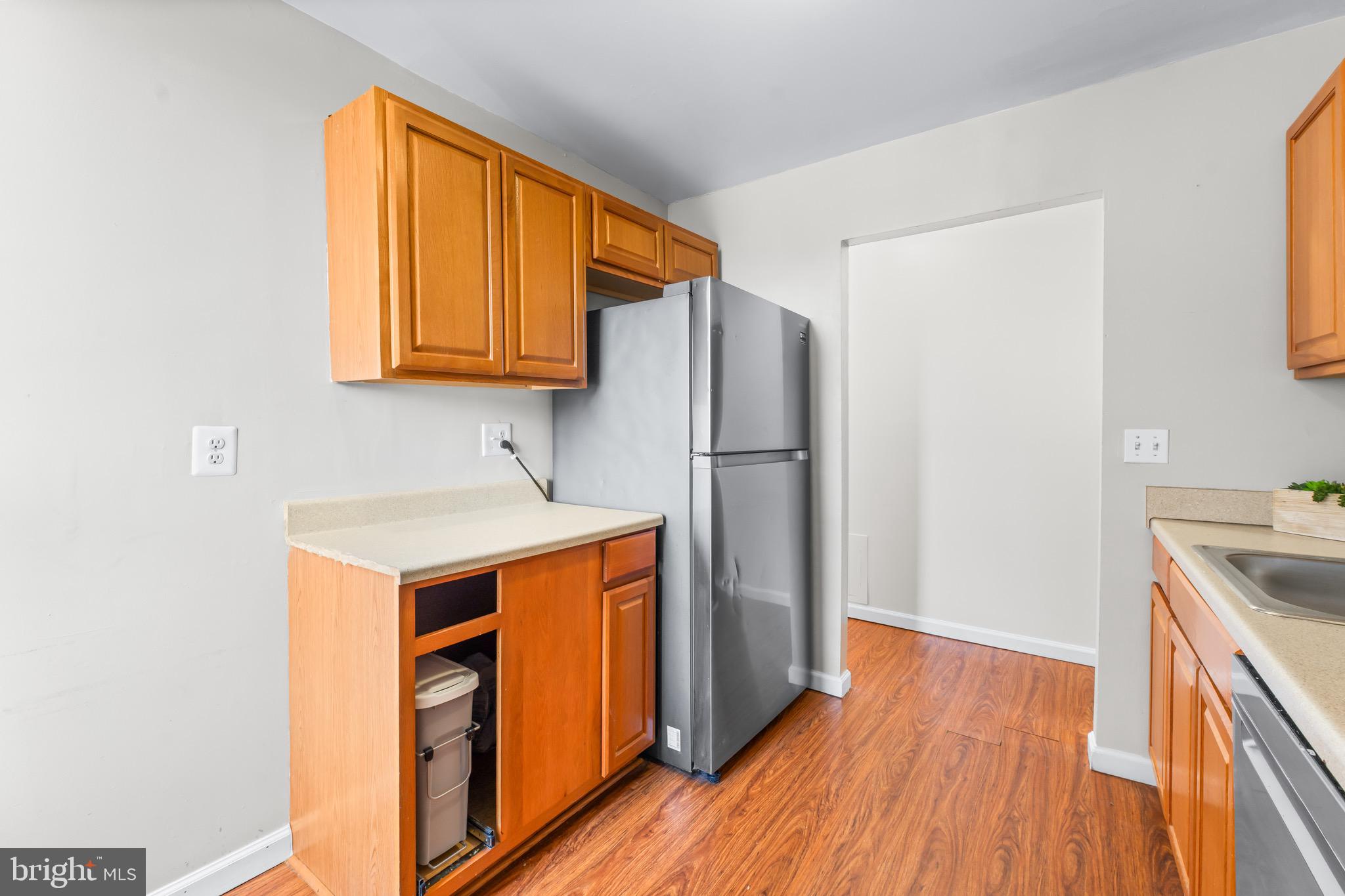 3340 Huntley Square Drive, Unit A Temple Hills, MD 20748 - Photo 18 of 19 a kitchen with stainless steel appliances granite countertop a refrigerator a sink dishwasher and wooden cabinets with wooden floor