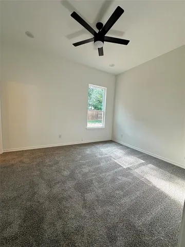 an empty room with a ceiling fan and windows