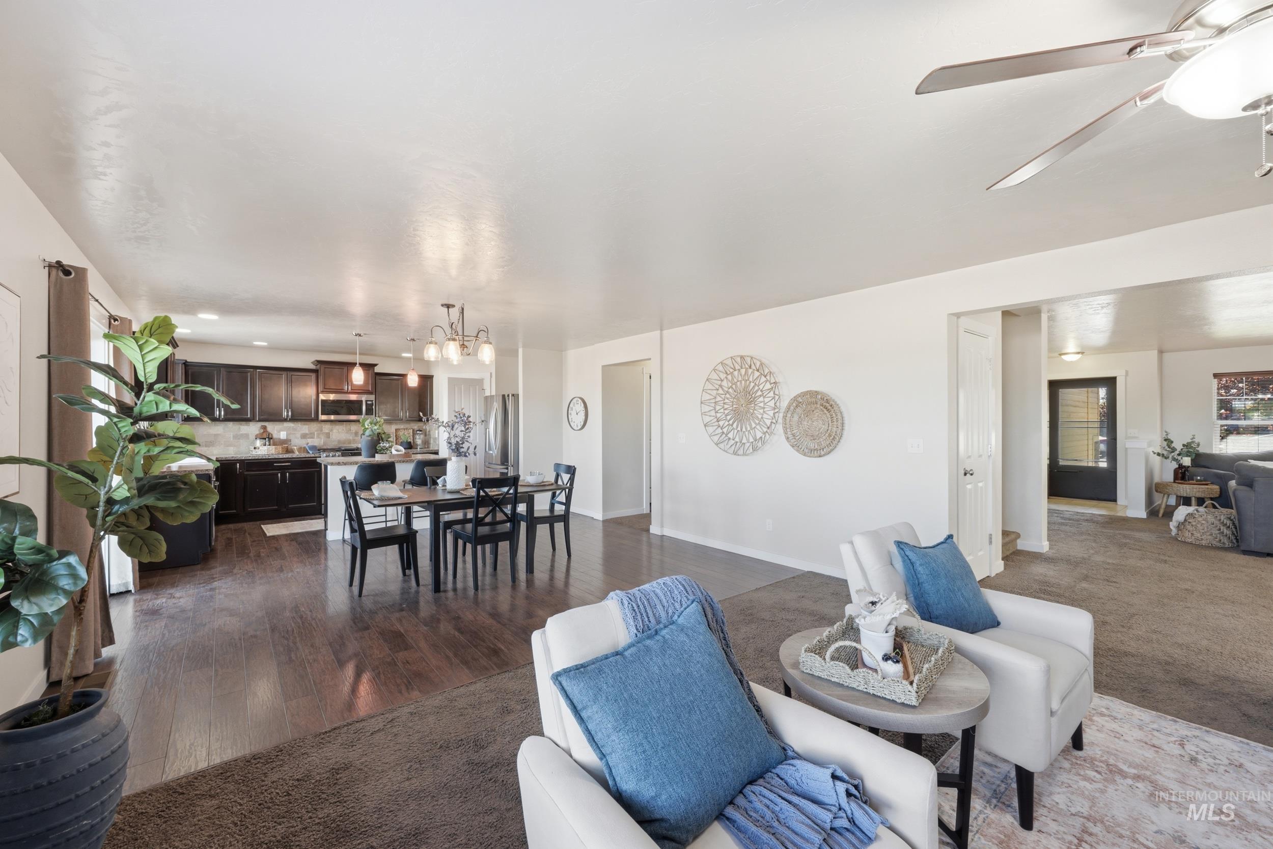 4855 South Chex Way Boise, ID 83709 - Photo 7 of 47 Open-concept living space featuring wood-finish flooring, a kitchen with dark cabinetry, a dining area with chandelier lighting, and a ceiling fan