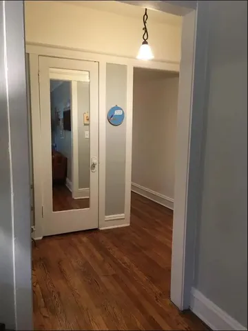 an empty room with wooden floor closet and windows