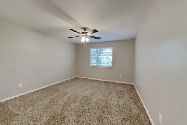 an empty room with windows and ceiling fan