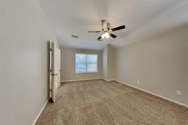 an empty room with windows and fan