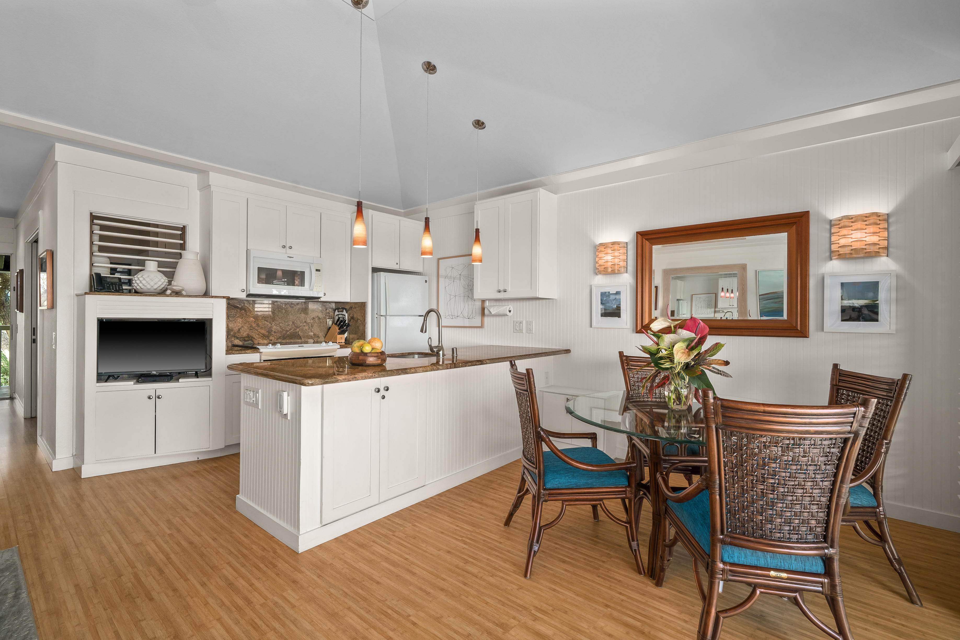 2253 Poipu Road, Unit 123 Koloa, HI 96756 - Photo 7 of 25 a kitchen with stainless steel appliances kitchen island wooden floors and white cabinets