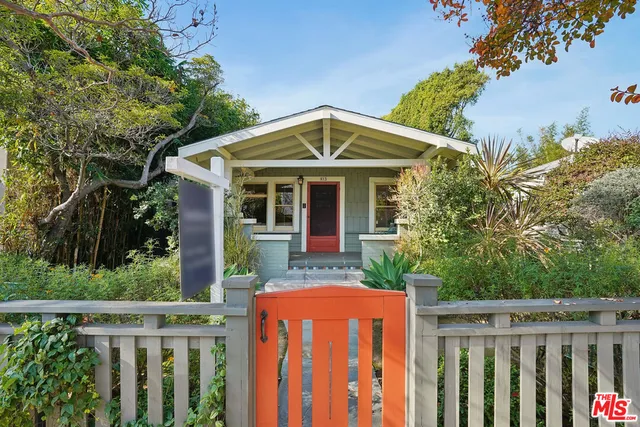 a view of a house with wooden fence next to a yard