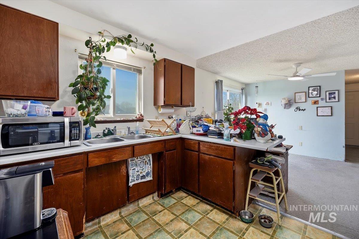 125 Sunset Circle Buhl, ID 83316 - Photo 8 of 17 Kitchen with ceiling fan, light countertops, a peninsula, light colored carpet, and stainless steel microwave