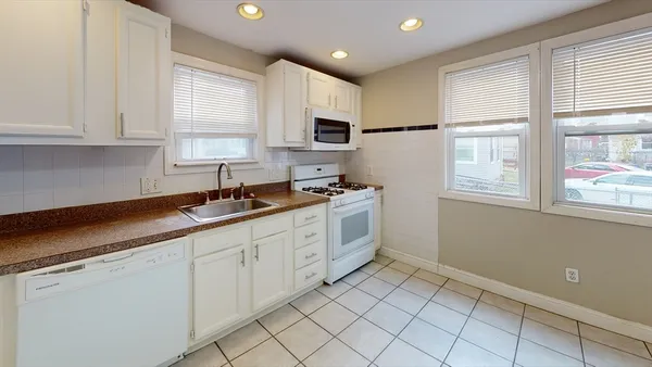 a kitchen with white cabinets and window