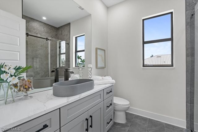 a bathroom with a granite countertop sink a large mirror a toilet and a shower