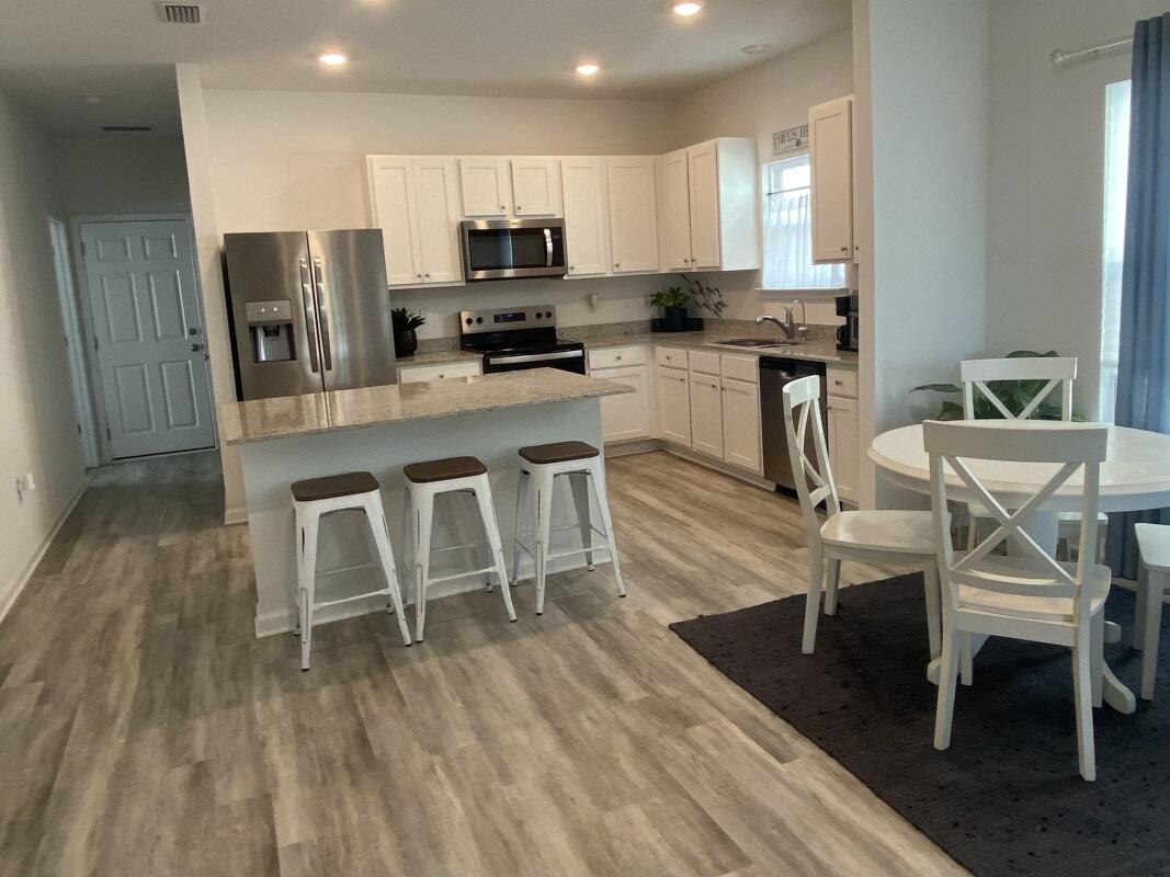 123 Staggerbush Street Freeport, FL 32439 - Photo 4 of 7 a kitchen with stainless steel appliances a dining table chairs microwave and sink