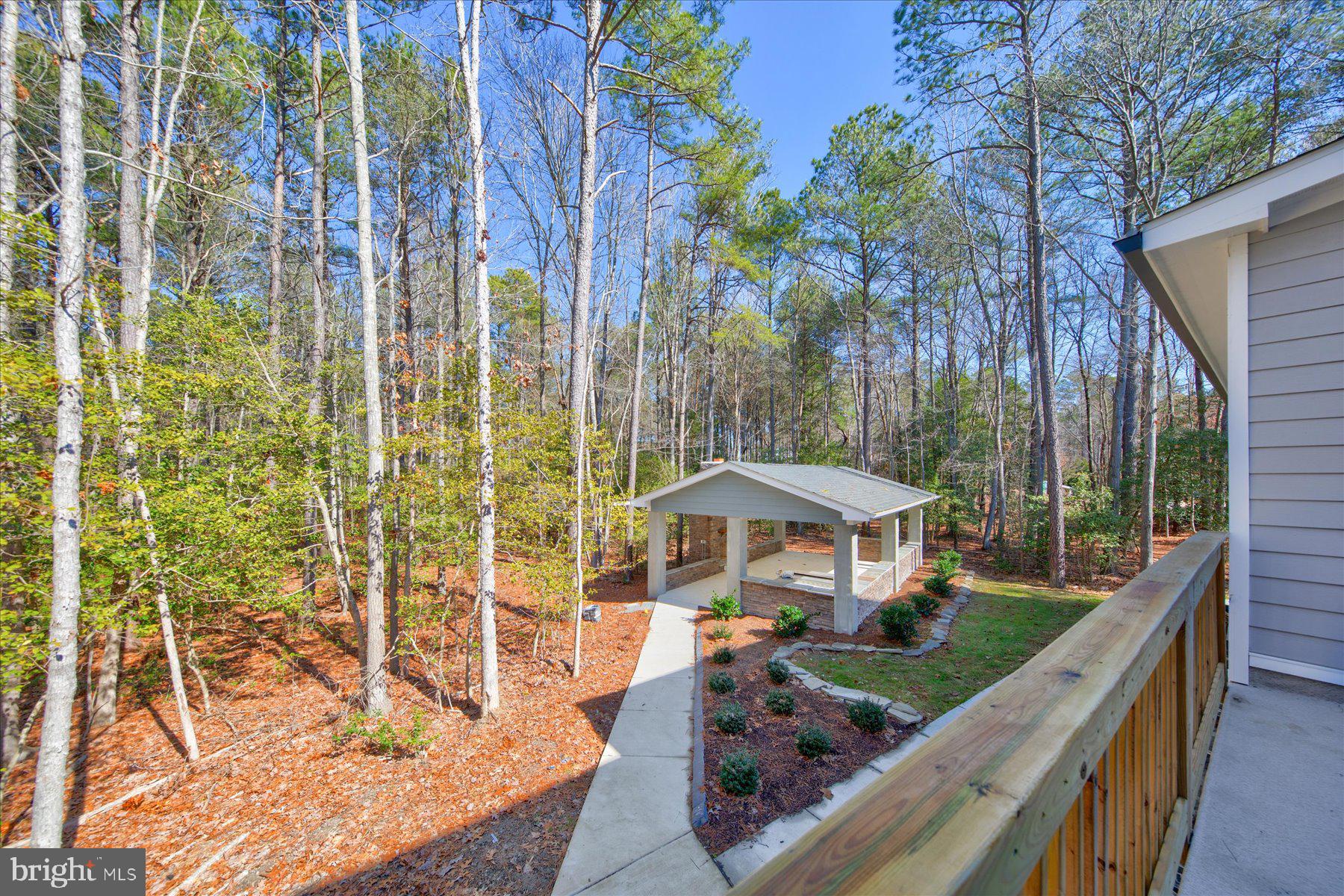 30425 Hollymount Road Harbeson, DE 19951 - Photo 87 of 98 a view of a patio with table and chairs under an umbrella with large trees