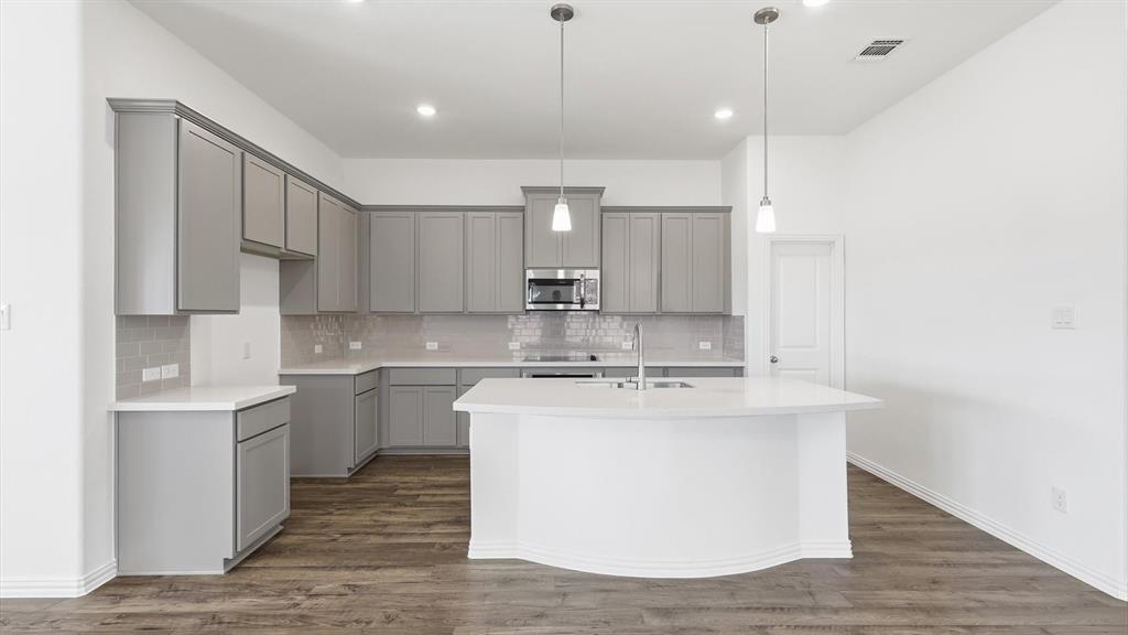 2529 Rivers W Road Anna, TX 75409 - Photo 20 of 40 Modern kitchen featuring light gray cabinetry, white countertops, a mosaic tile backsplash, stainless steel appliances, and a central island with pendant lighting