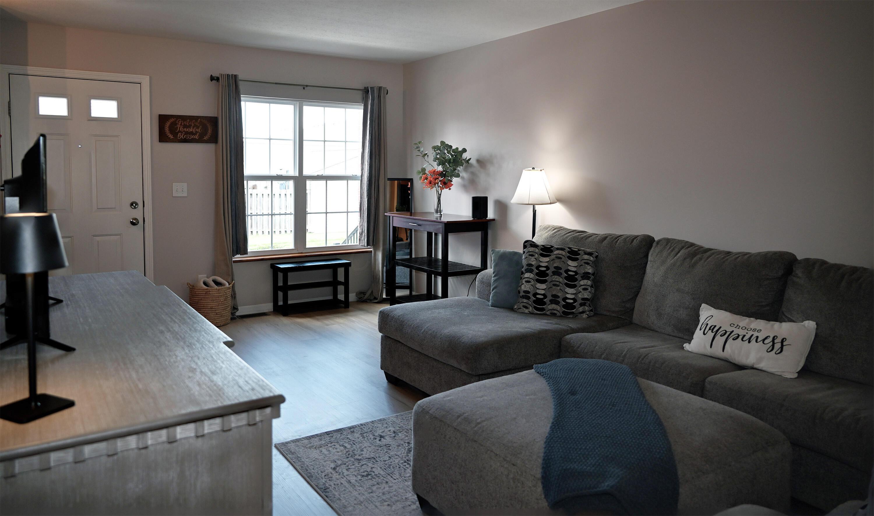 8289 Bruntsfield Road Columbus, OH 43235 - Photo 4 of 36 Bright and inviting living room featuring luxury vinyl plank flooring, large front-facing window, neutral décor, and an open layout ideal for relaxing or entertaining.