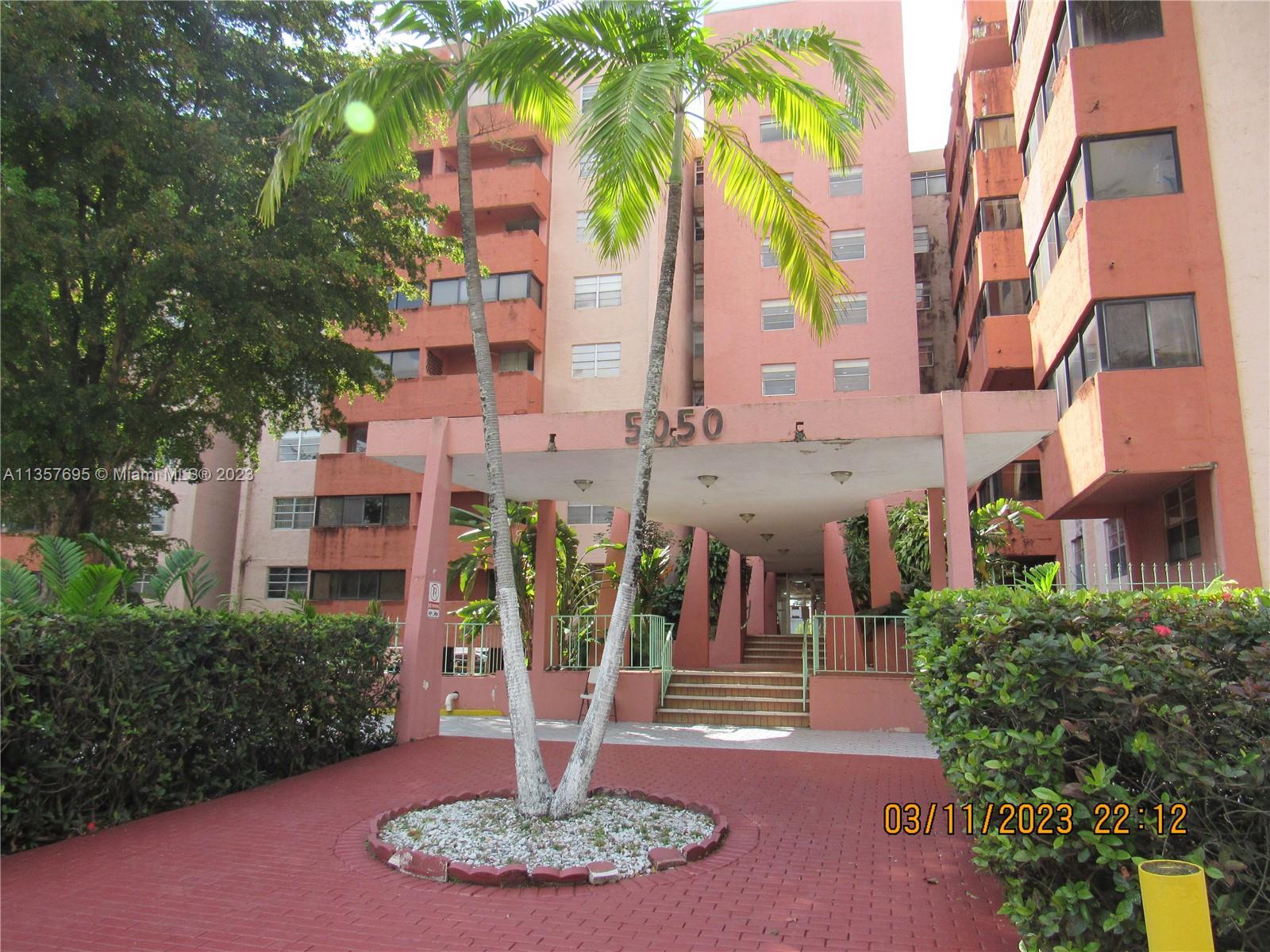 a front view of a multi story residential apartment building with yard and green space