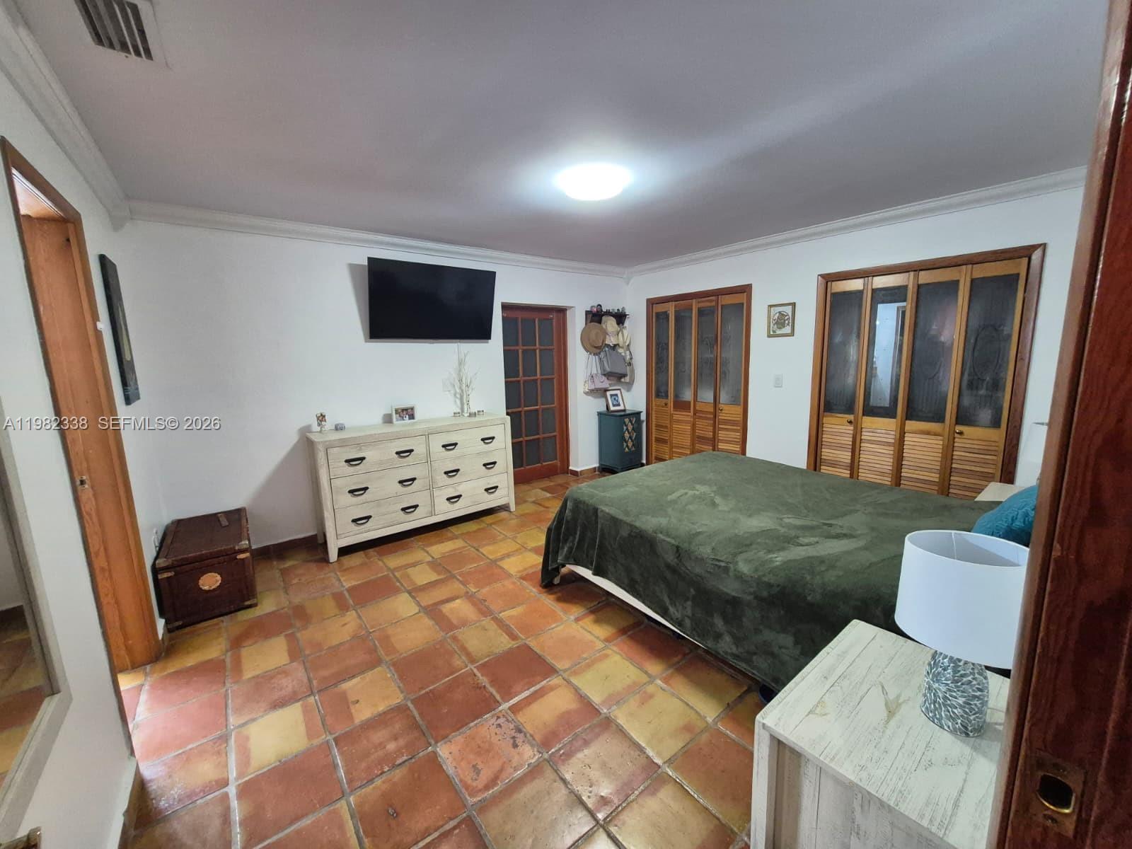 14530 Southwest 110th Street Miami, FL 33186 - Photo 18 of 45 a bedroom with a bed and a flat tv screen on dresser