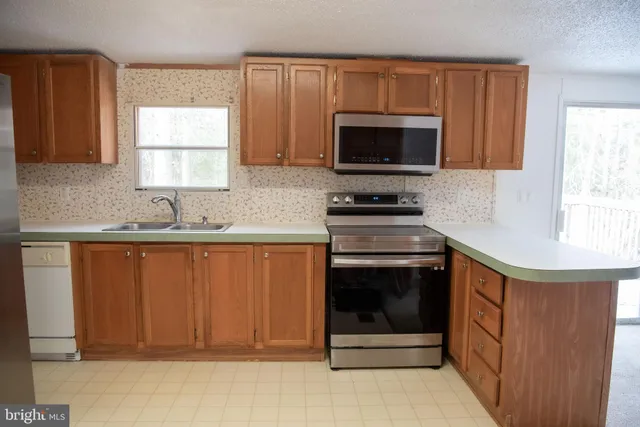 a kitchen with granite countertop a sink stove and microwave