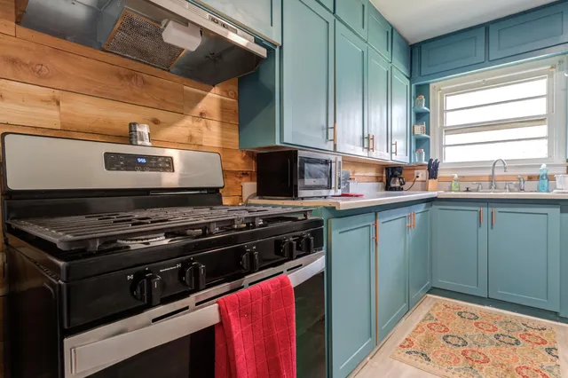 a kitchen with stainless steel appliances granite countertop a stove a sink and a microwave