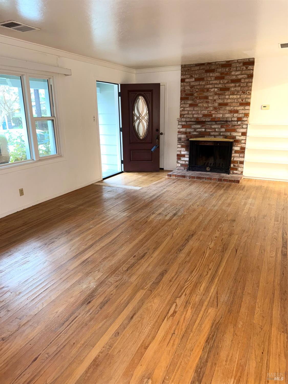 3469 Idaho Drive Santa Rosa, CA 95405 - Photo 5 of 31 LIVING ROOM - Carpet has been removed to reveal original wood floors which are in average condition and worn, need to be re-finished. The home was re-leveled in December 2025, settlement cracks (in earlier photos) have been patched and walls touched up.