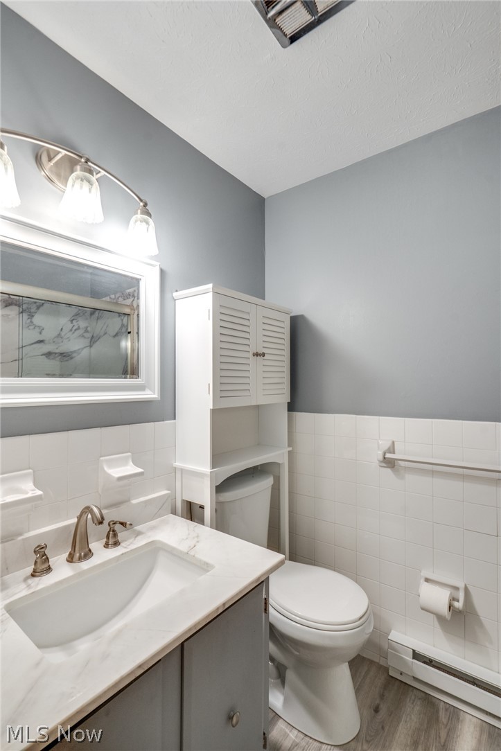 3070 Kent Road Stow, OH 44224 - Photo 36 of 43 Bathroom with vanity, a baseboard heating unit, tile walls, light flooring, and a wainscoted wall