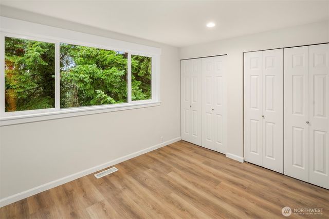 a view of an empty room with a window and hardwood floor