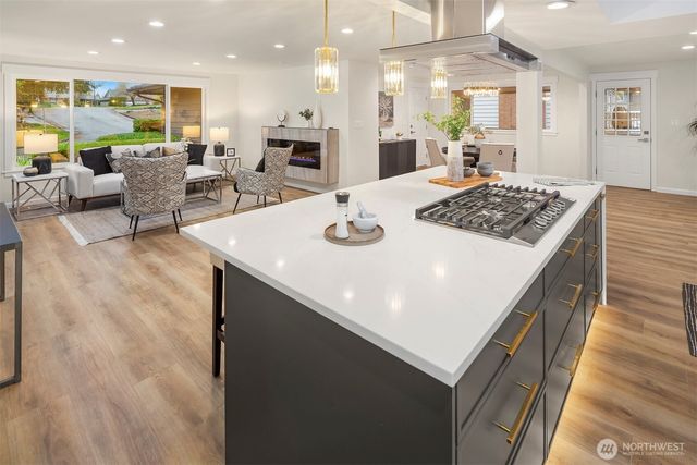 a large kitchen with stainless steel appliances granite countertop a stove top oven a sink dishwasher a dining table and chairs with wooden floor