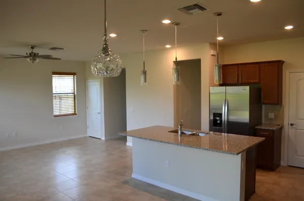 a large kitchen with kitchen island granite countertop a refrigerator a sink and a stove