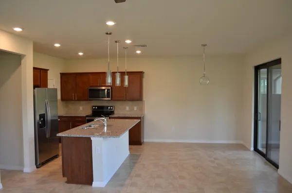 a kitchen with kitchen island stainless steel appliances a sink a refrigerator a stove a microwave and cabinets