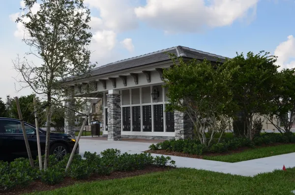a front view of a house with a garden and trees
