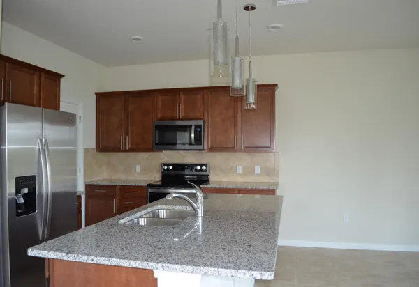 a kitchen with stainless steel appliances granite countertop a sink a stove and a refrigerator