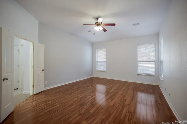 a view of an empty room with wooden floor and a window