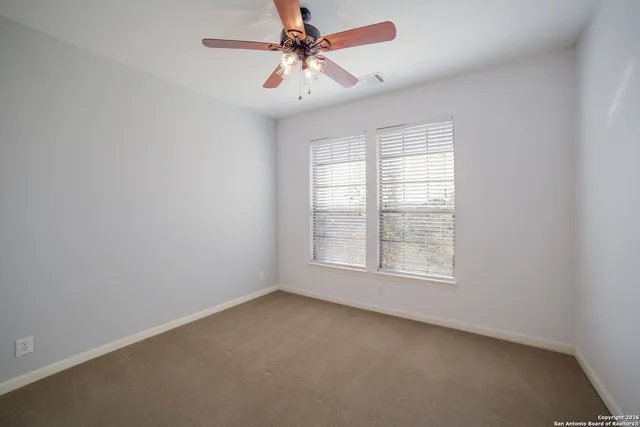 an empty room with a window and a fan