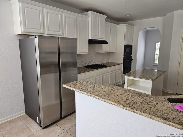 a kitchen with stainless steel appliances granite countertop a refrigerator a stove and a sink