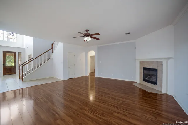 a view of an empty room with wooden floor and a fireplace