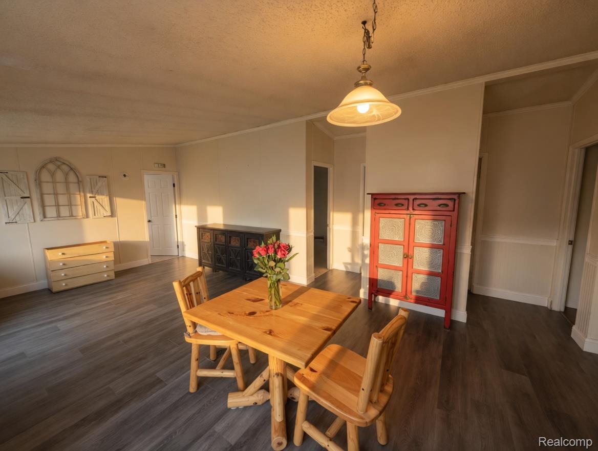6988 McKean Road Ypsilanti, MI 48197 - Photo 8 of 31 Dining area featuring dark wood finished floors, ornamental molding, and a textured ceiling