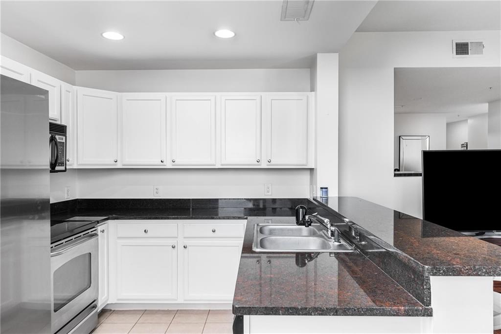 3040 Peachtree Road, Unit 1205 Atlanta, GA 30305 - Photo 5 of 43 a kitchen with granite countertop white cabinets and black appliances