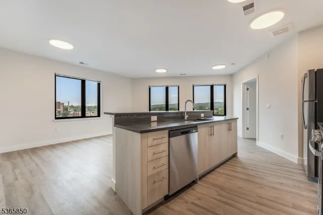 a large kitchen with stainless steel appliances granite countertop a lot of counter space and wooden floor