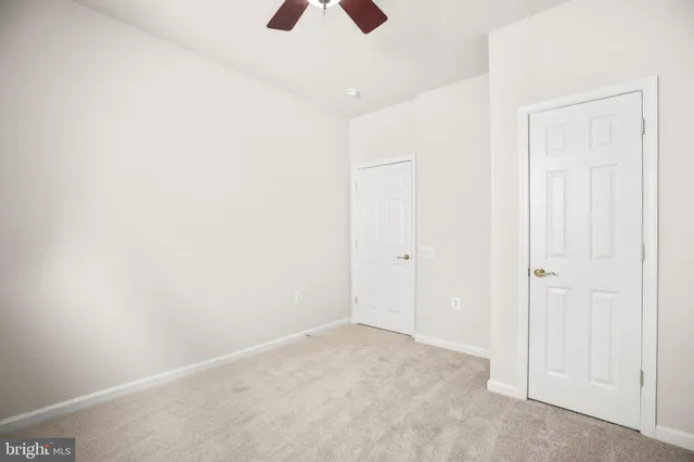 an empty room with a ceiling fan and windows