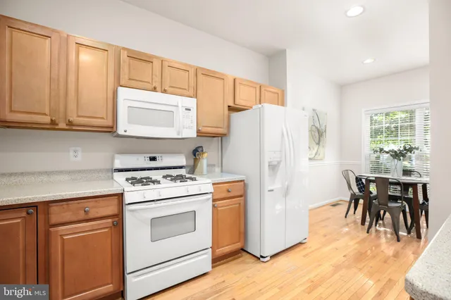 a kitchen with a refrigerator stove and white cabinets with wooden floor