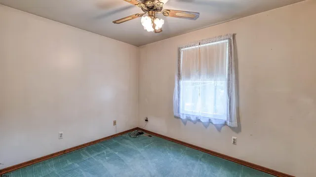 an empty room with a window and a chandelier fan